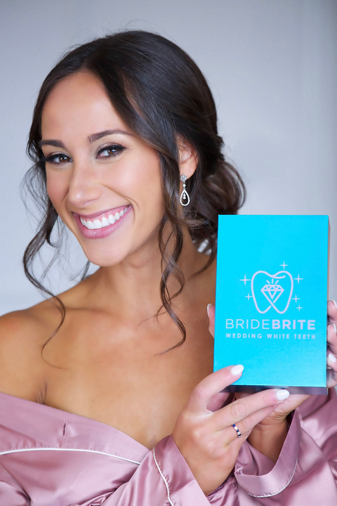 Bride in a blush robe holding her Bride Brite whitening kit